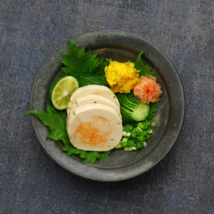 Monkfish liver slices served with garnishes and vegetables on a grey plate