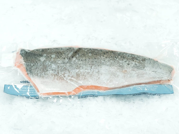 Vacuum-sealed 'Copper River' king salmon fillet, showing the intact skin and vibrant color through the transparent packaging, emphasizing its freshness and quality preservation