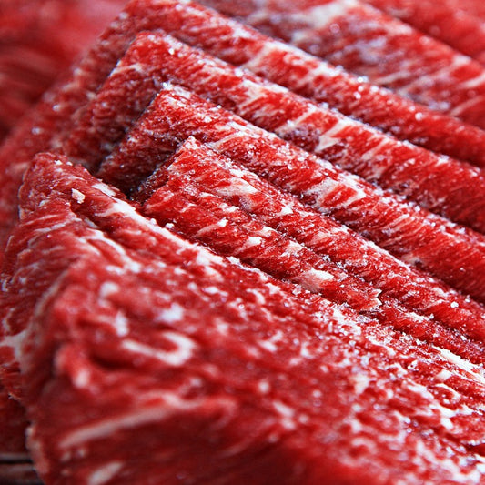 소고기 꽃등심 슬라이스의 근접 촬영, 섬세한 마블링과 밝은 붉은 색의 고기가 특징, 각 슬라이스는 정교하게 정렬되어 있으며, 결정화된 소금과 지방층이 보임