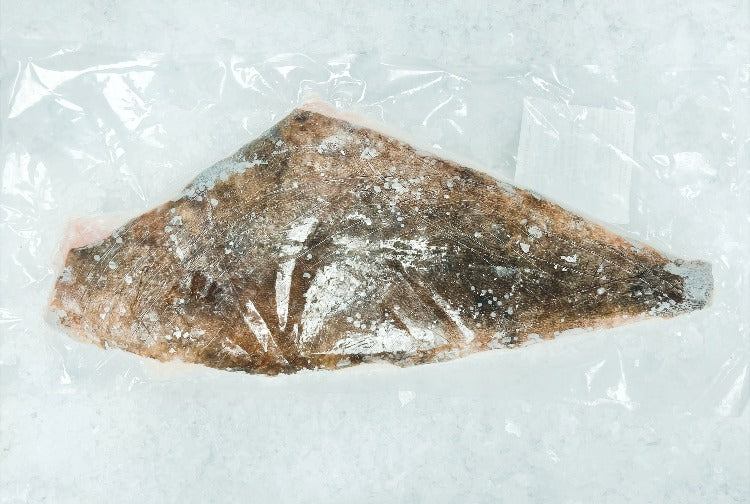 Frozen halibut fillet vacuum-sealed in plastic packaging, ready for sale