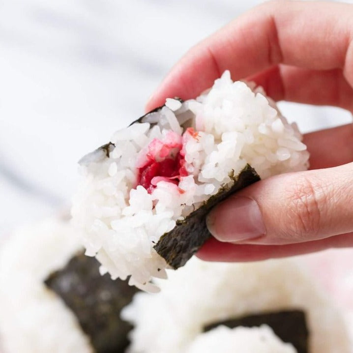 Hand holding rice ball filled with plum paste