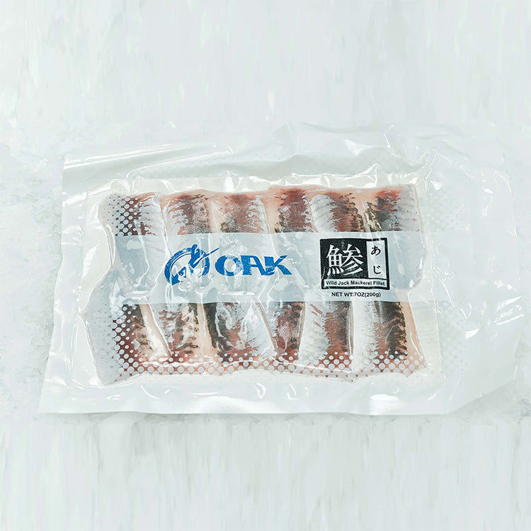 Vacuum-sealed package of wild jack mackerel fillets (Aji), neatly arranged in rows. The clear packaging showcases the fillets' fresh and high-quality appearance, with the OAK brand logo and product name in Japanese characters