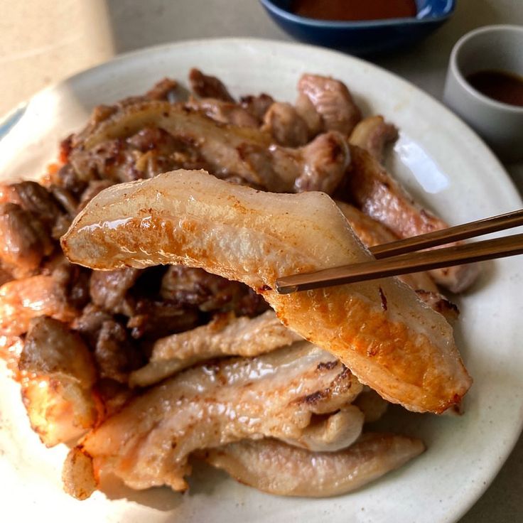 "Deliciously grilled pork jowl slices presented on a ceramic plate, ready to be enjoyed with dipping sauce. A popular choice for savory meat dishes