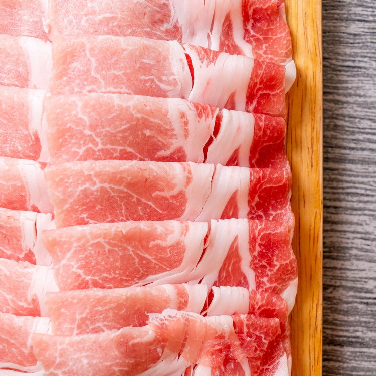 Layered slices of fresh pork shoulder on a wooden tray, showcasing the delicate marbling and tender texture. Ideal for hotpot, barbecue, or gourmet cooking