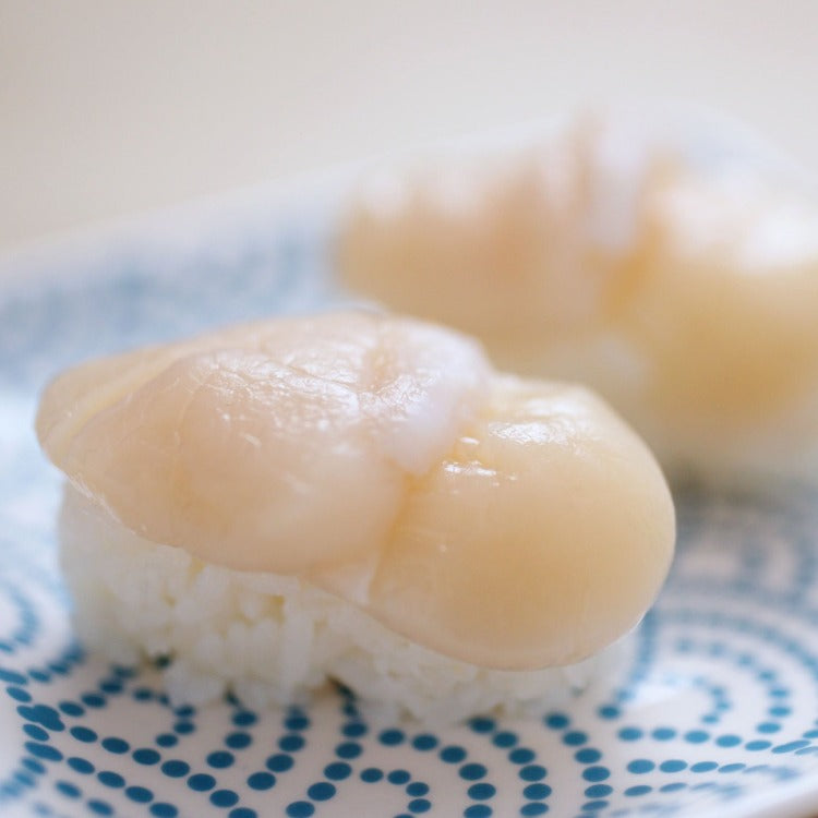 Delicate scallop nigiri sushi served on a blue and white patterned plate