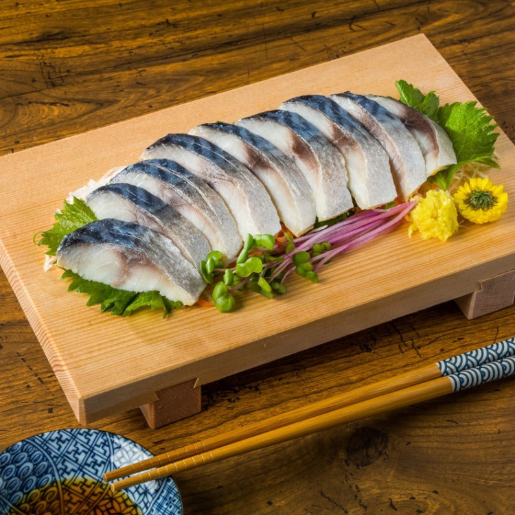 Elegantly arranged marinated mackerel sashimi on a wooden platter, garnished with fresh greens and wasabi