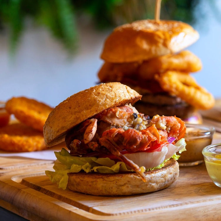 Gourmet soft shell crab burger served on a wooden board with lettuce and sauce. Perfect for seafood lovers and burger enthusiasts