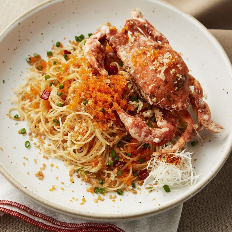 Delicious soft shell crab pasta garnished with herbs and roe, served in a white bowl. Ideal for a flavorful and unique seafood pasta dish