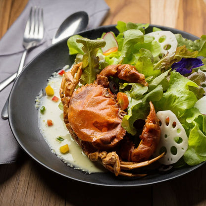 Fresh and vibrant soft shell crab salad with mixed greens and lotus root, served on a black plate. A healthy and delicious seafood salad option