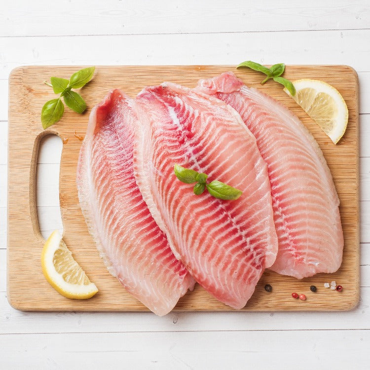 Raw Tilapia Fillets on Wooden Cutting Board with Lemon and Basil