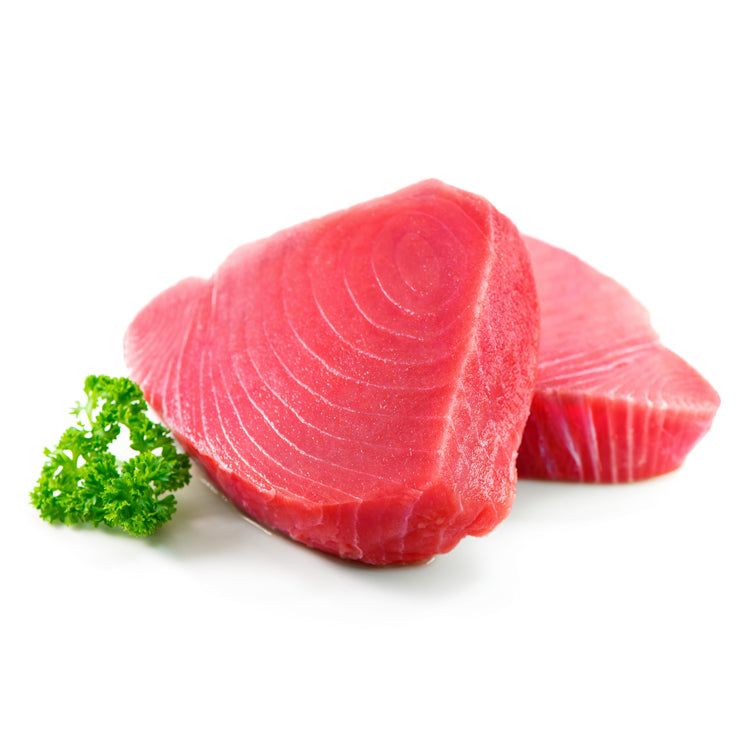 Fresh bluefin tuna steak on a white background garnished with a sprig of parsley, showcasing the fish's intense red color and clean lines