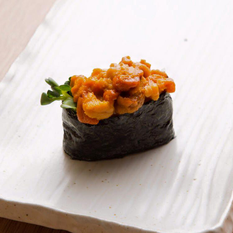 Fresh uni sea urchin roe held by chopsticks - exquisite delicacy for sushi and sashimi