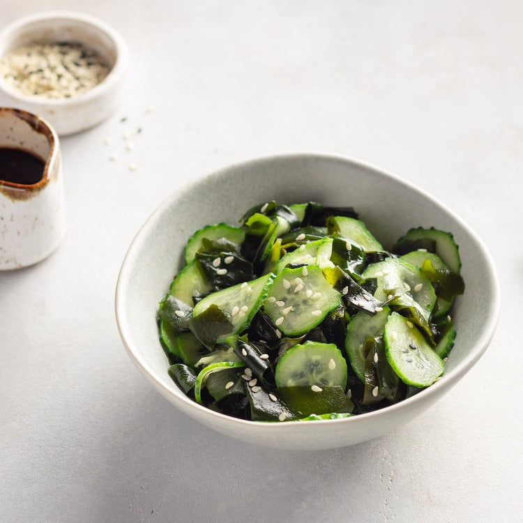 A bowl of cucumber salad topped with sesame seeds.