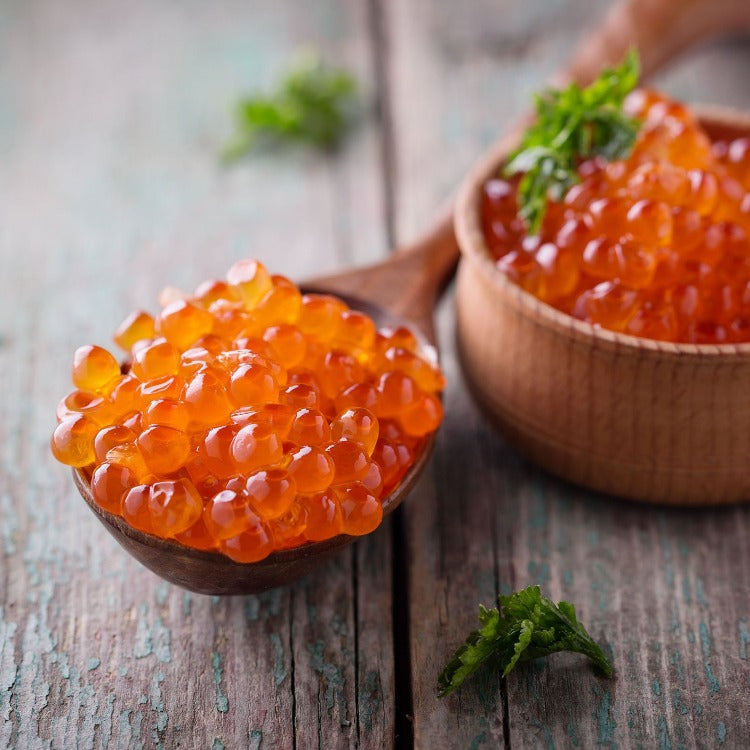 Fresh Ikura (Salmon Roe) in a wooden bowl and spoon on a rustic table