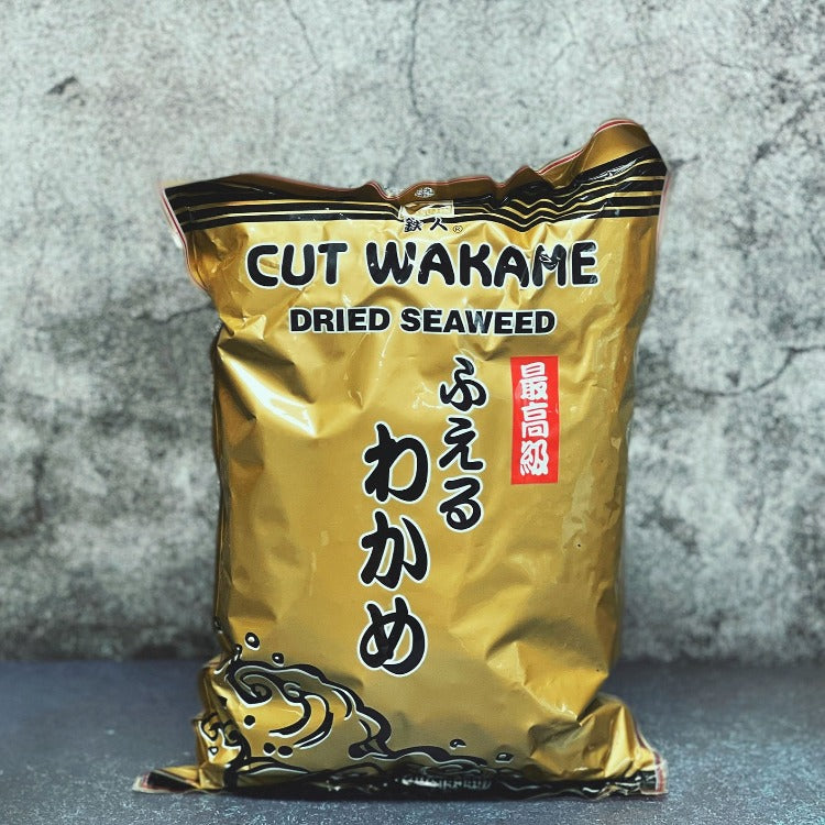 A gold-colored package of cut wakame dried seaweed against a grey background. The packaging has text in both English and Japanes