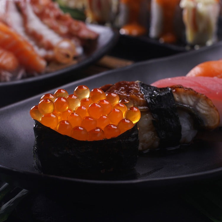 Ikura (Salmon Roe) sushi roll with nori on a black plate